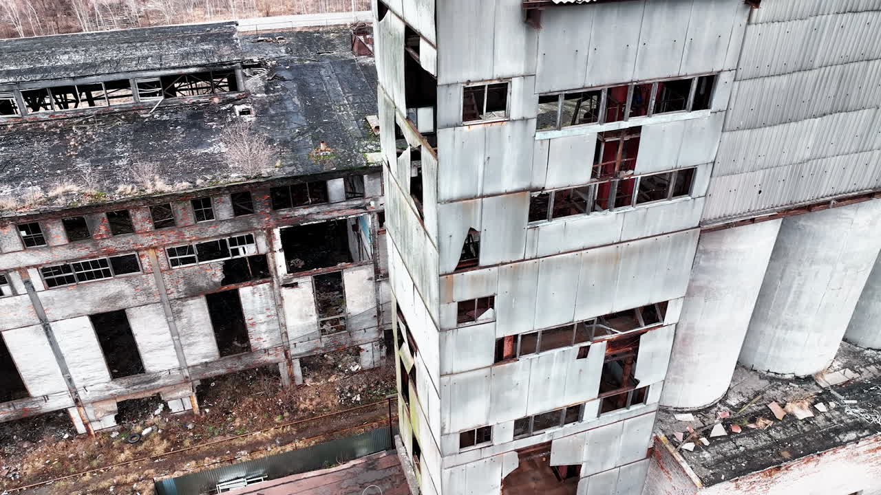 Old plant territory abandoned long ago. Grey wrecked skeletons of the industrial premises. View from above.