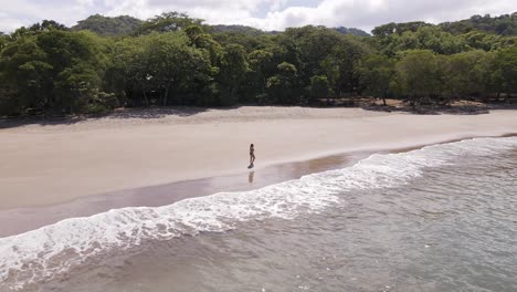 young white woman in bikini walking along the lush, empty shore of playa real in guanacaste, costa rica