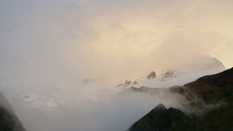 himalayas mountains in sunset clouds in moody atmospheric scene of annapurna mountain range in nepal with beautiful dramatic orange sunset sky with peaks in the clouds