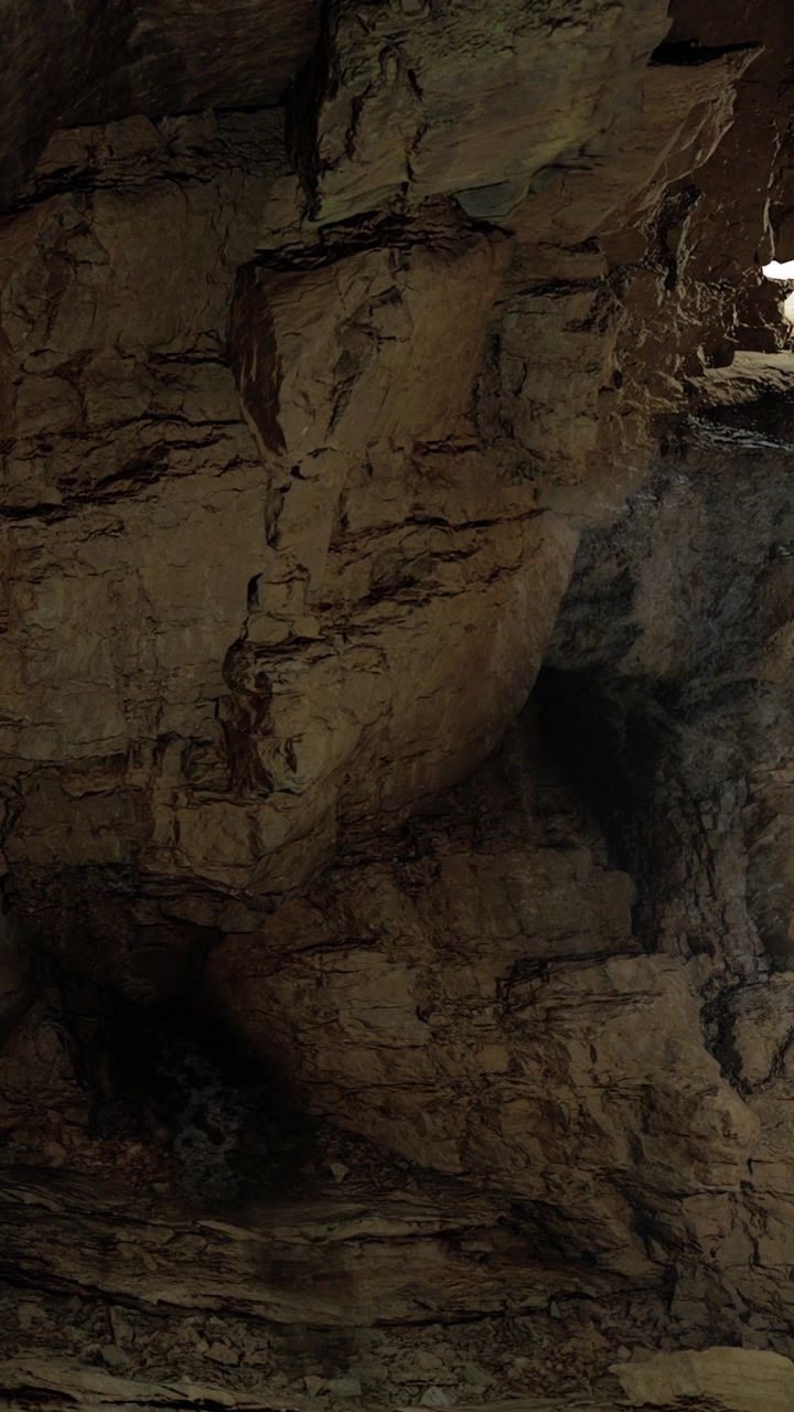 Grotta con grandi rocce e una piccola apertura che fornisce luce dall'alto.