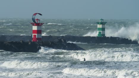 odważny kitesurfer jeździ na dużych burzliwych falach, które gwałtownie rozbijają się i rozpryskują na molo