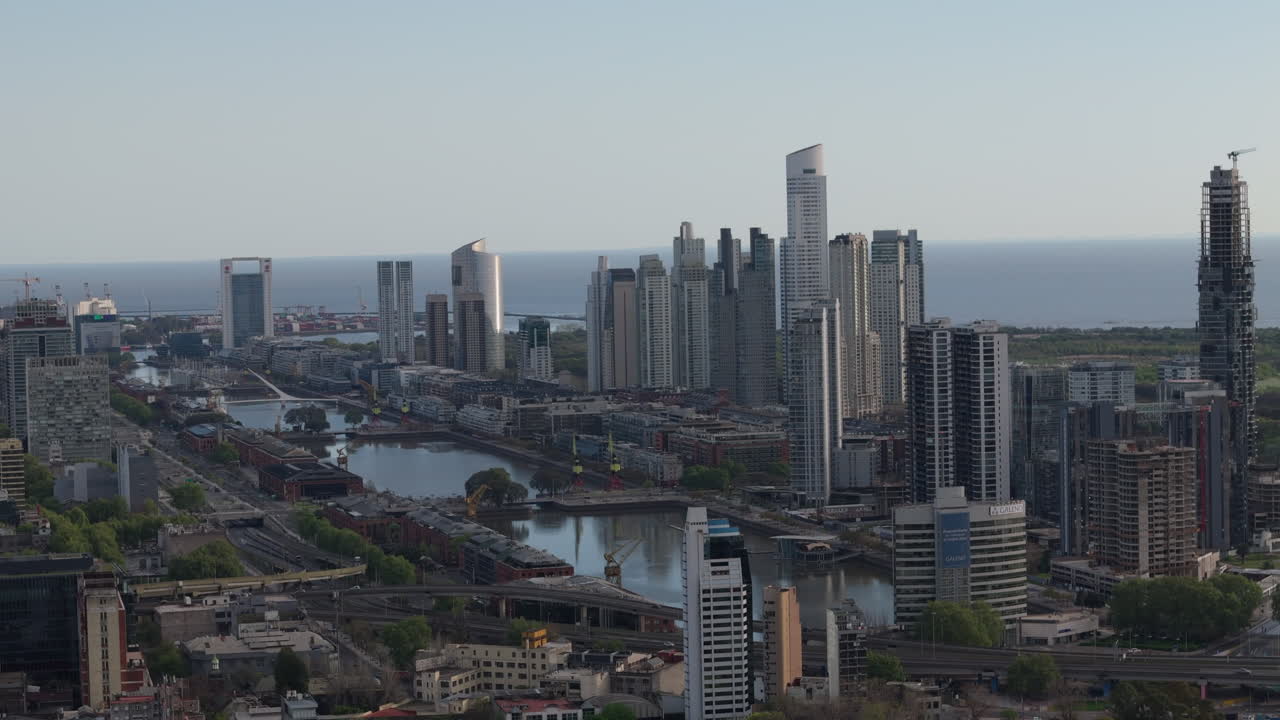 Capturing the stunning skyline of puerto madero area. This aerial image showcases modern skyscrapers and bridges long the river and canals at sunset