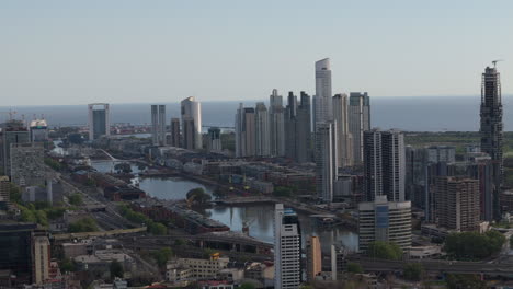 capturing the stunning skyline of puerto madero area. this aerial image showcases modern skyscrapers and bridges long the river and canals at sunset