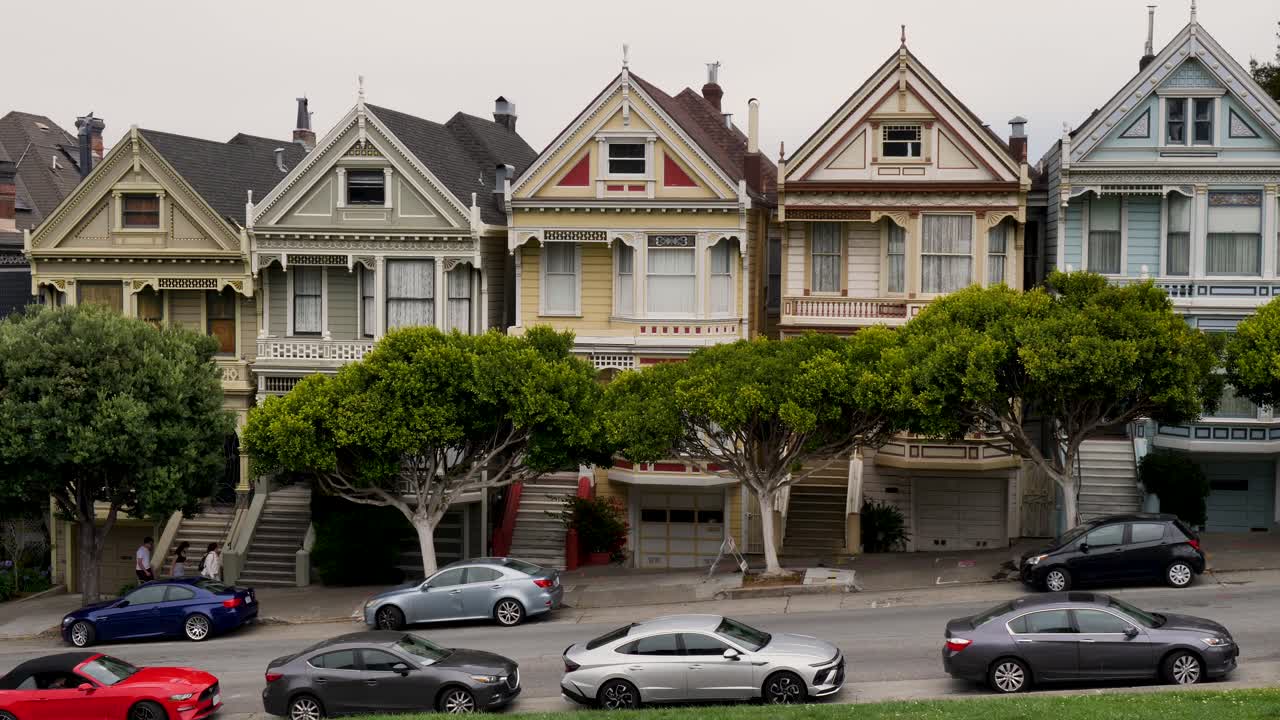 Slow motion landscape of the Painted Ladies Victorian housing homes buildings architecture with cars parked in street Alamo Square San Francisco city California USA travel tourism