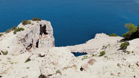 drone shot flying over cliffs and mountains on coast of ibiza island