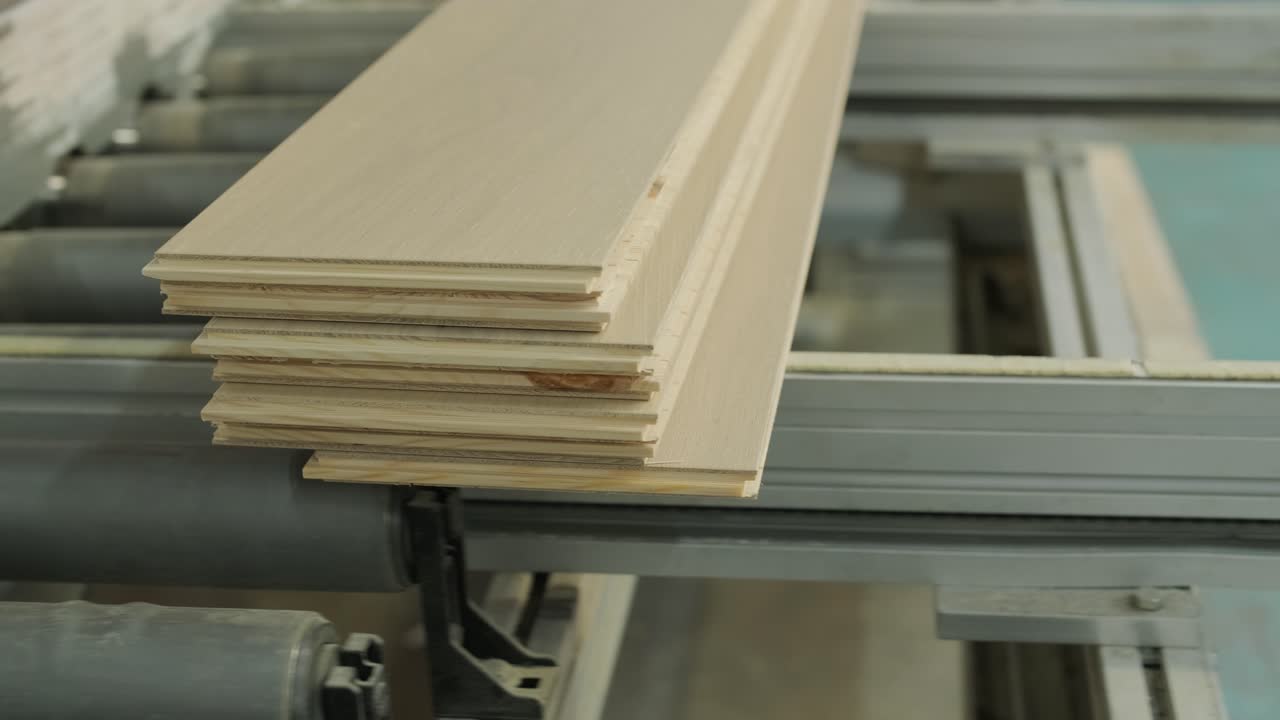 Lavoratore posiziona assi di legno su nastro trasportatore in fabbrica di lavorazione del legno