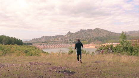hombre en forma corriendo y deteniéndose para ver la vista de un lago con presa