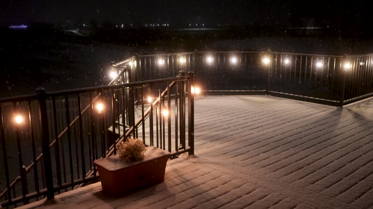 nieve fresca que cae suavemente en una noche tranquila - vista estática de un patio o terraza iluminados