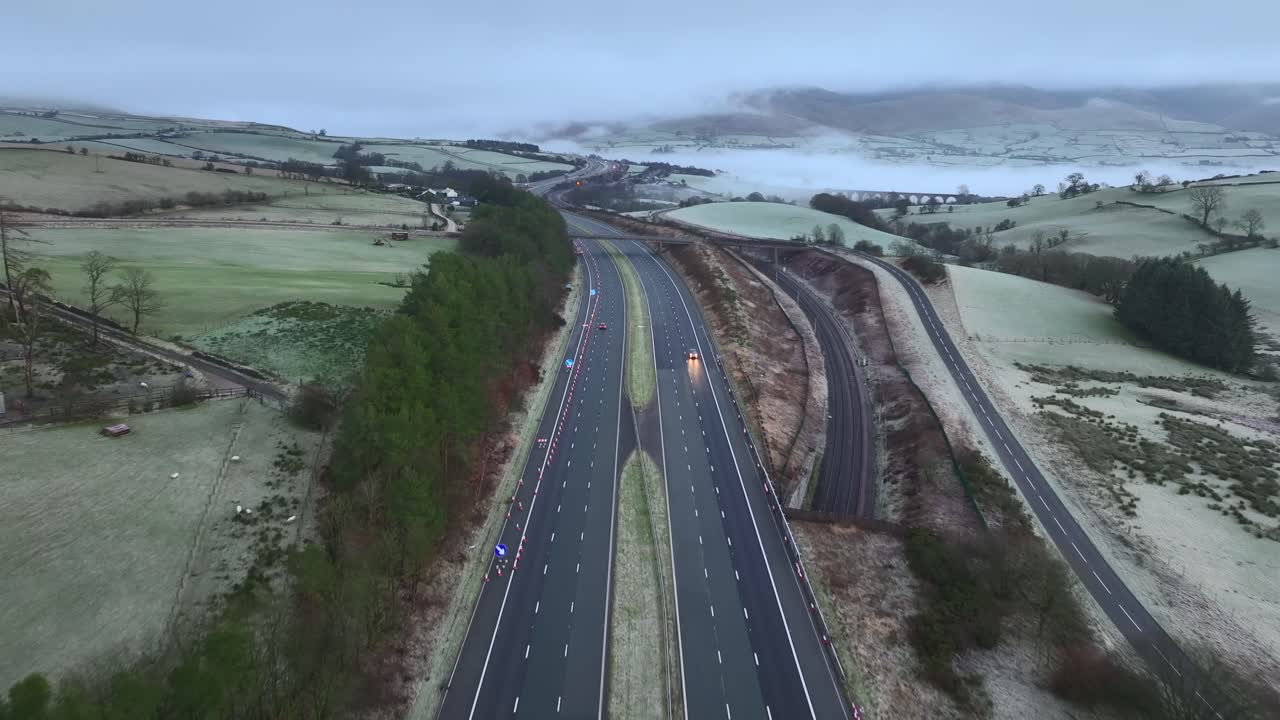 volando por el centro de la autopista m6 con tráfico ligero al amanecer en invierno con colinas de fondo cubiertas de niebla, niebla y nubes bajas