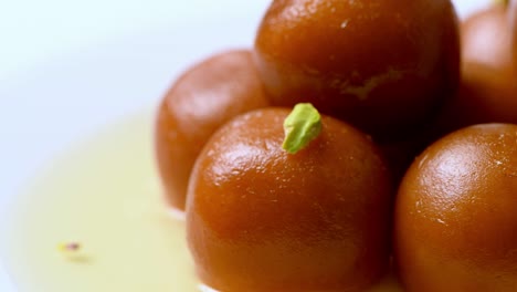 gulab jamun girando con pistacho encima ( dulce indio ) | postre | toma de primer plano