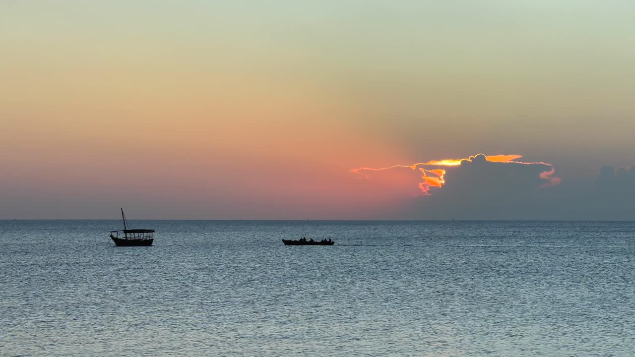 Two boats meet on the coast of Stone Town after sunset. Zanzibar, Tanzania.