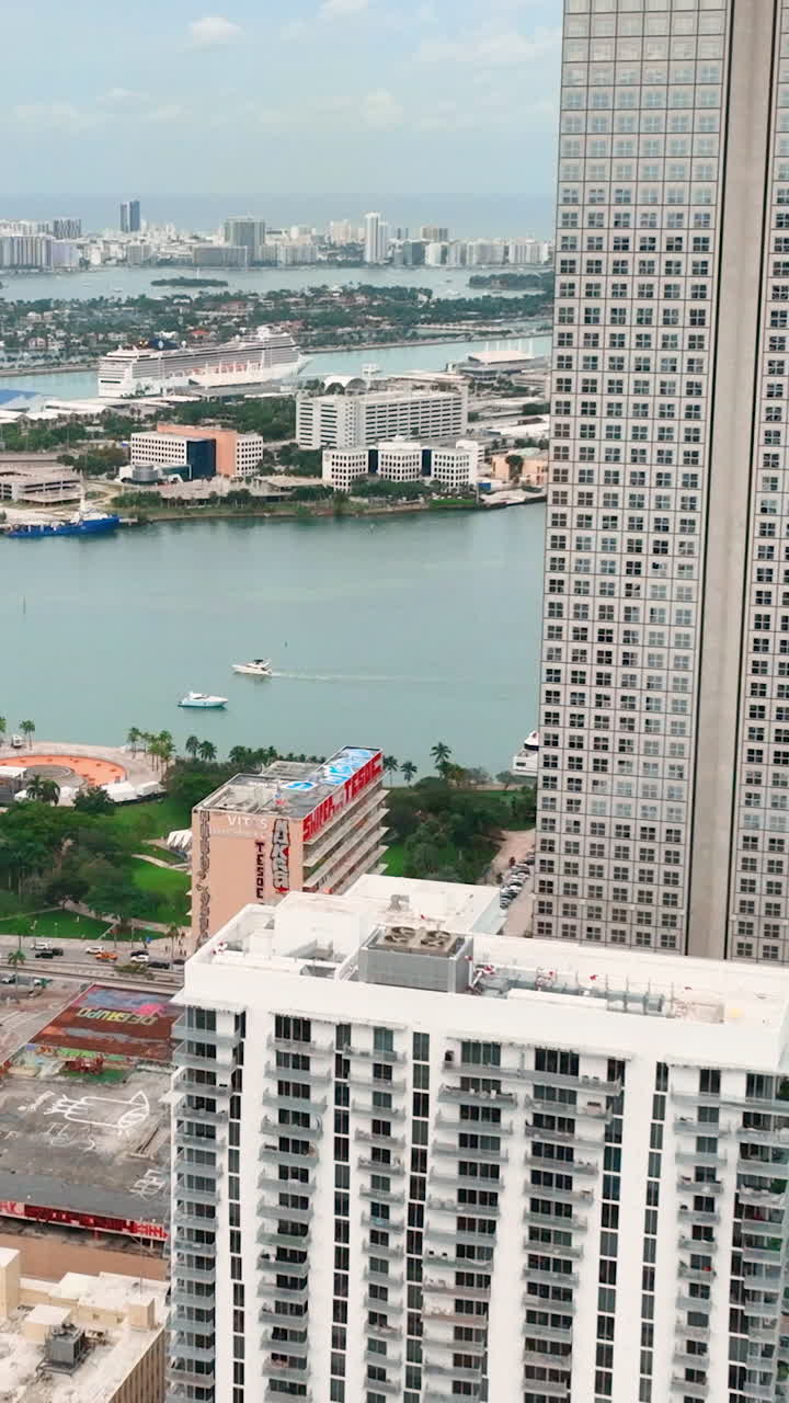 Miami, Florida, USA - January 05, 2024: Aerial view from above of downtown Miami skyscrapers on the bay with port and cruise ships in the Atlantic Ocean. Vertical video