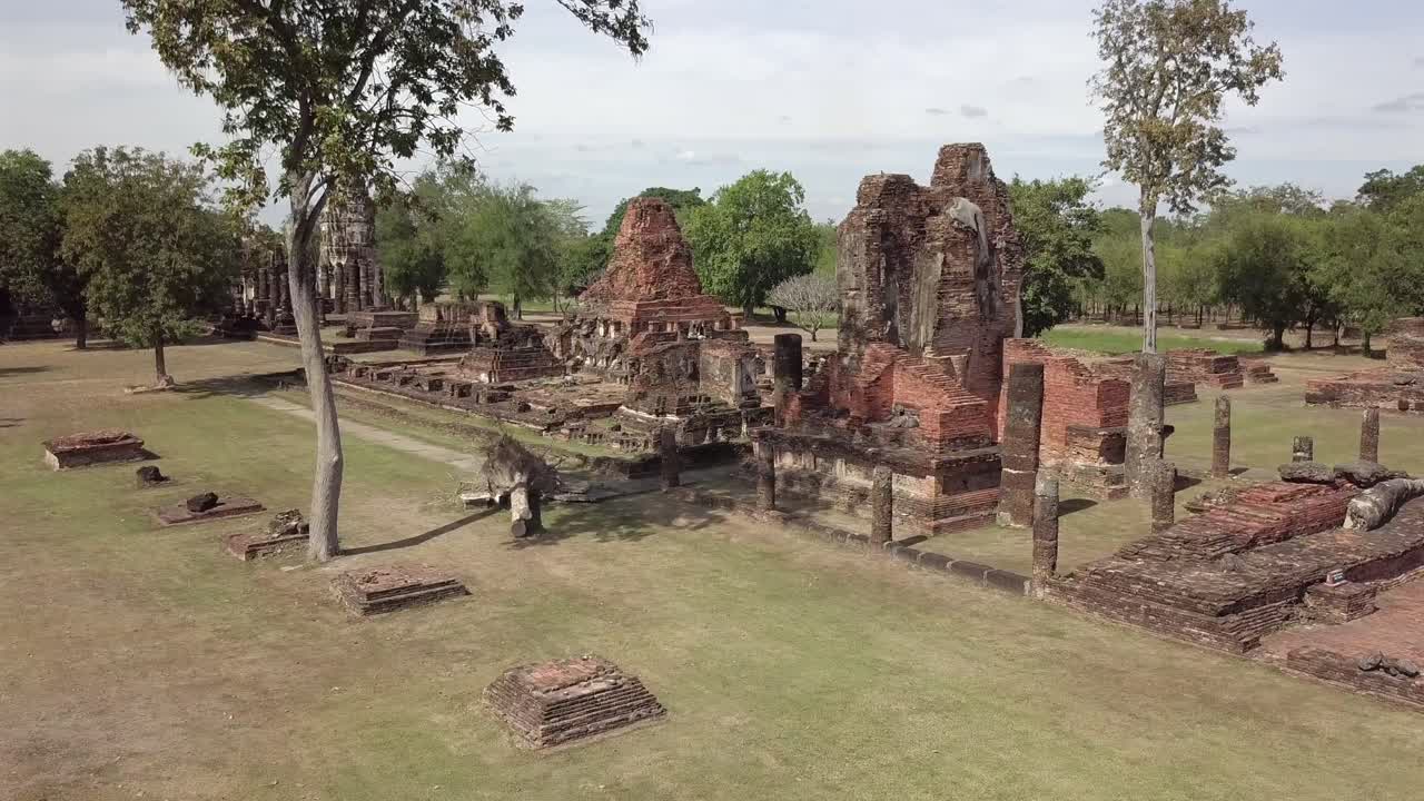 Aerial view pan left and forward towards covering temple complex of Wat Phra Phai Luang,Sukhothai historical park on a sunny day.