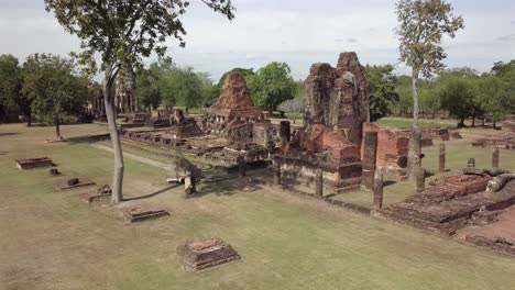 aerial view pan left and forward towards covering temple complex of wat phra phai luang,sukhothai historical park on a sunny day.