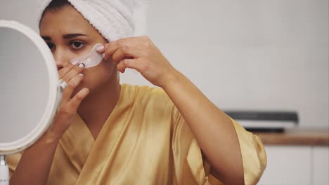 closeup portrait of beautiful woman after bath with towel on head puts patches under the eyes from wrinkles and dark circles.