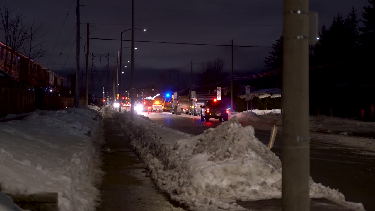 Removing snow from suburban streets at night in Ottawa with snow plows and blowers.