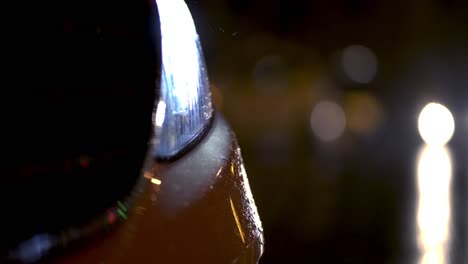 closeup of rain hitting a cars front light in the night