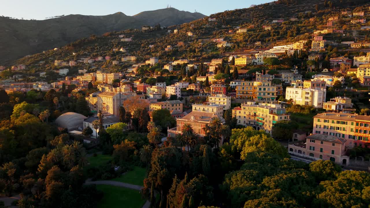 Sunset drone shot over Genoa, Italy, showing colorful houses and lush greenery