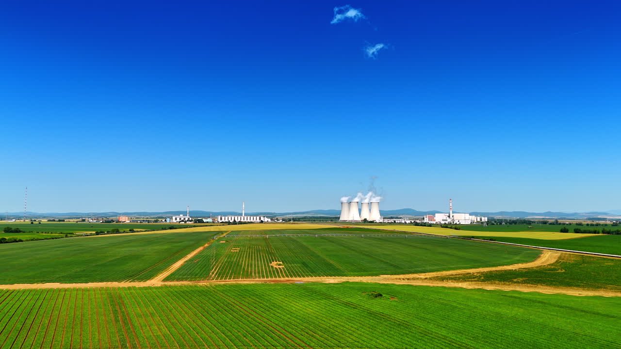 Modern industrial plant working in the countryside. White smoke rises into the air from the huge pipes. Aerial view