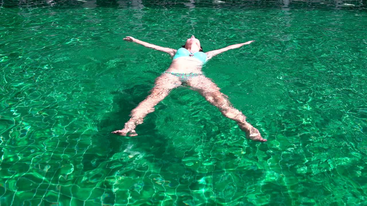 수영복 을 입은 여자 가 수영장 에 누워 있다