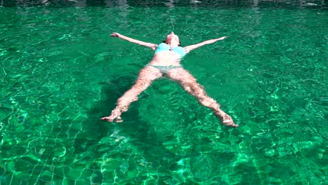 mujer en traje de baño yace en la piscina