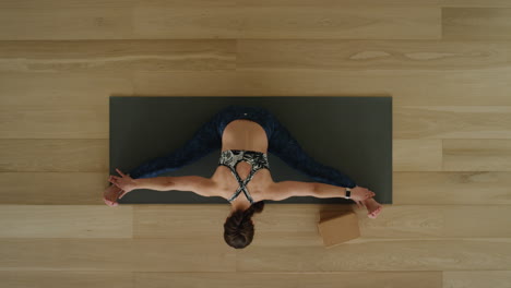 above view yoga woman practicing seated forward bend pose in workout studio enjoying healthy lifestyle meditation practice training on exercise mat