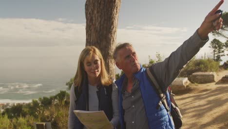 pareja de ancianos activos buscando el mapa en el bosque