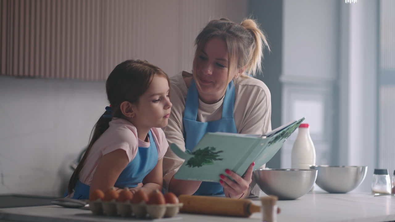 mujer y su hija pequeña están leyendo libro de cocina cocina de la casa en domingo madre está enseñando a su hijo a cocinar