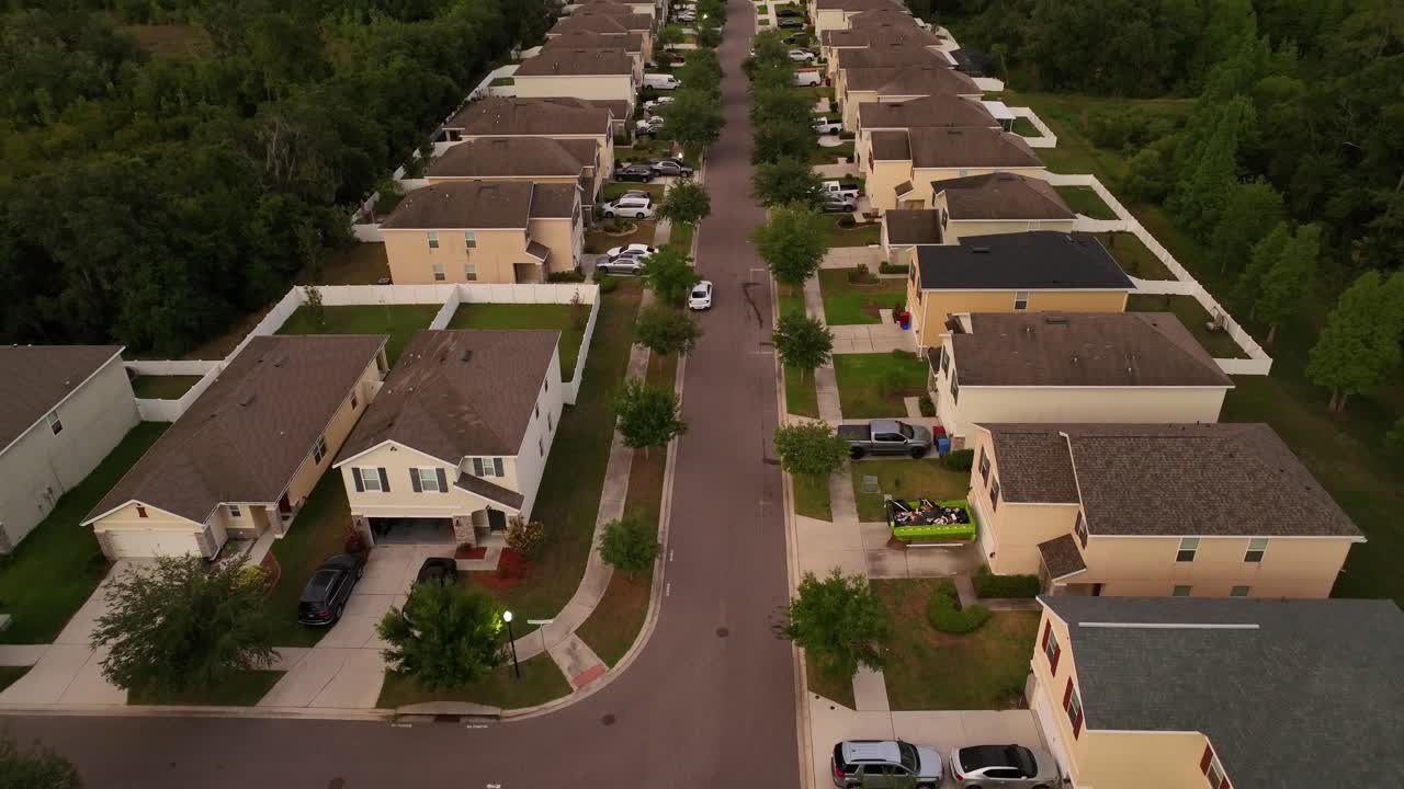 Aerial view of Florida neighborhood with charming two-story uniform houses with spacious driveways, manicured lawns and neat, symmetrical designs. Parking cars at sunset time. Brandon, USA.