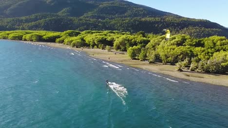 Aerial-dolly-in-of-sportsman-doing-kitesurfing-at-Puelo-Lake,-mountains-in-background,-Patagonia-Argentina