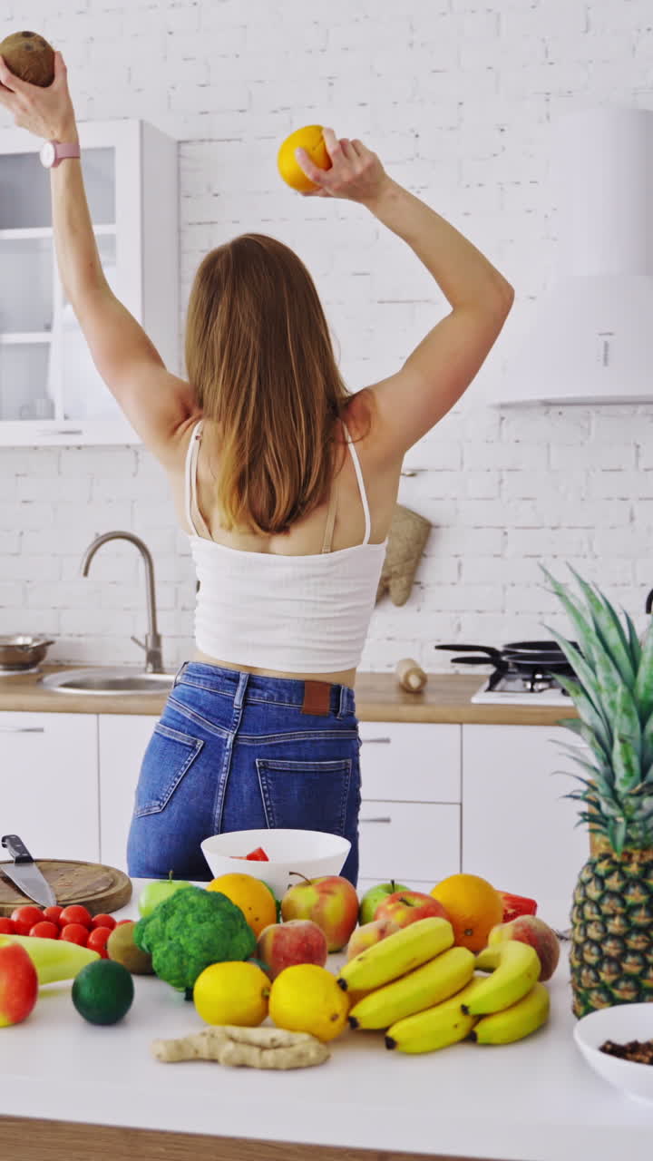 Smiling woman with fruits. Happy smiling woman with fruits having fun in modern kitchen Vertical video