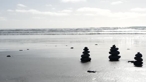 rock balancing on ocean beach, stones stacking by sea water waves. pyramid of pebbles on sandy shore