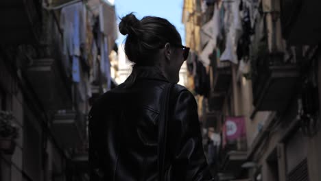 retrato de una alegre joven caucásica con sonrisas de gafas de sol mirando a la cámara en las coloridas calles de barcelona, españa, cierre medio del día, cámara lenta, portátil