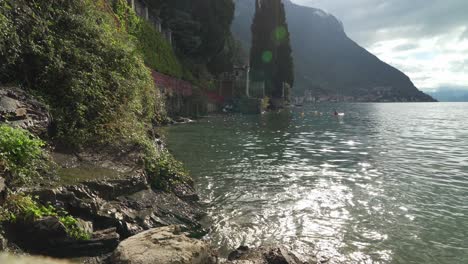 water splashes against rocky coast of town varenna in lake como