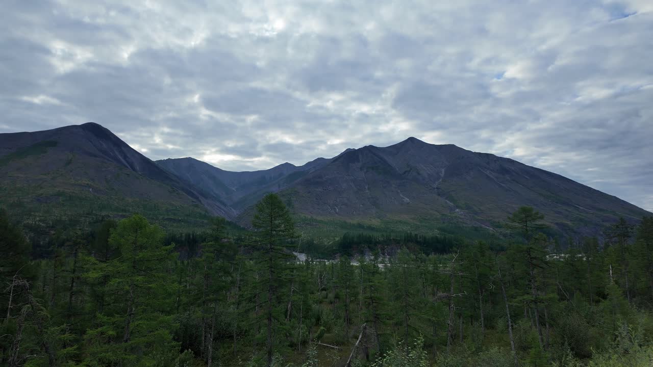 sea testigo de la impresionante belleza de yakutia mientras la luz del sol baila sobre majestuosas montañas, rodeadas de exuberantes bosques y un cielo sereno.