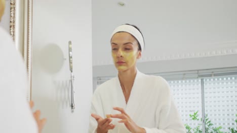mujer caucásica mirándose en el espejo y haciendo maquillaje en el baño