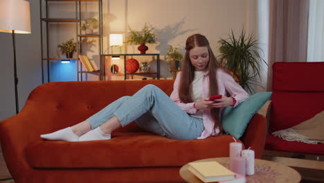 young teen child girl at home, using smartphone share messages on social media, watching relax movie