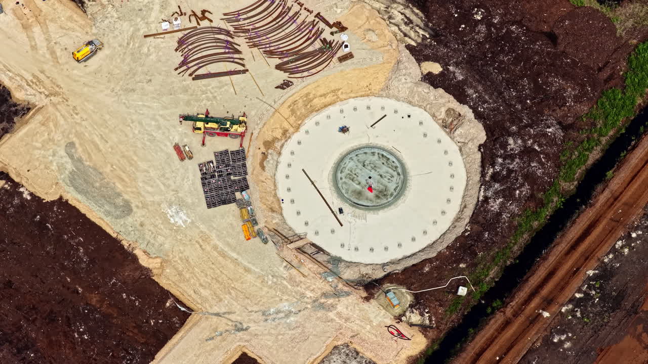 Wind turbine foundation construction site with materials and equipment arranged on ground