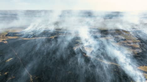 Smoke-lingering-over-freshly-burnt-prairie-after-controlled-burn-in-the-Flint-Hills-of-Kansas,-Drone-Shot