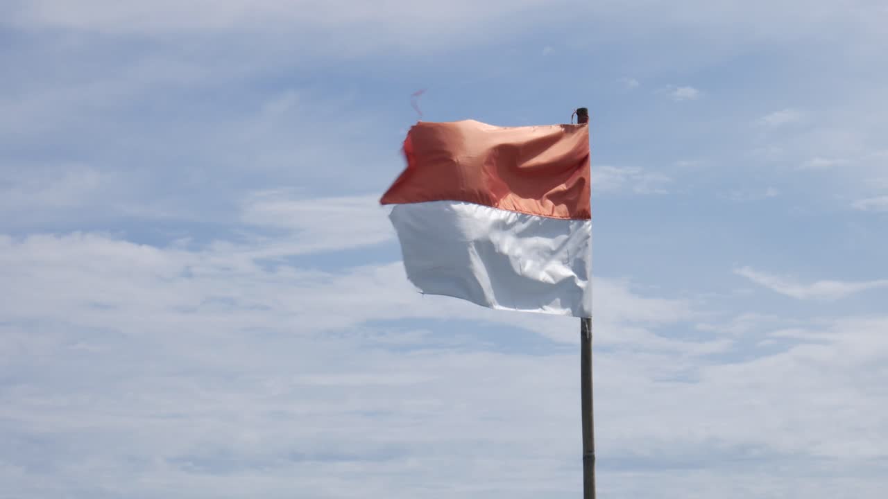bandera indonesia ondeando en el asta de la bandera contra el fondo del cielo azul