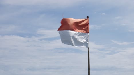 bandera indonesia ondeando en el asta de la bandera contra el fondo del cielo azul