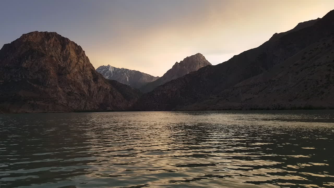 el agua glacial del lago iskanderkul, provincia de sughd, tayikistán, asia con la puesta de sol sobre los picos de las montañas