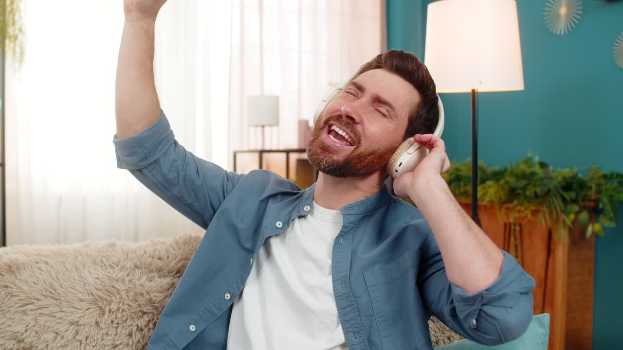 Man enjoying music with headphones nodding rhythmically moving hands feeling the beat at home