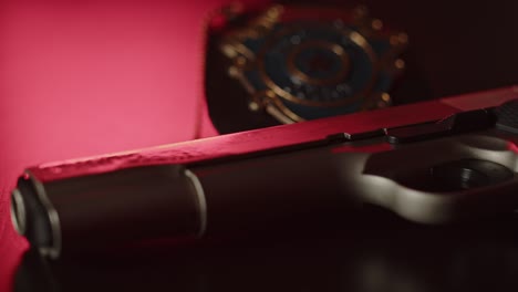 Close-up-of-gun-barrel-with-a-police-badge-in-the-background