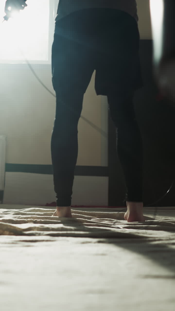 el atleta se prepara para saltar en la cuerda en el gimnasio de combate de cerca. el maestro de artes marciales hace ejercicios con la cuerda de salto en el club deportivo en cámara lenta. inventario de entrenamiento