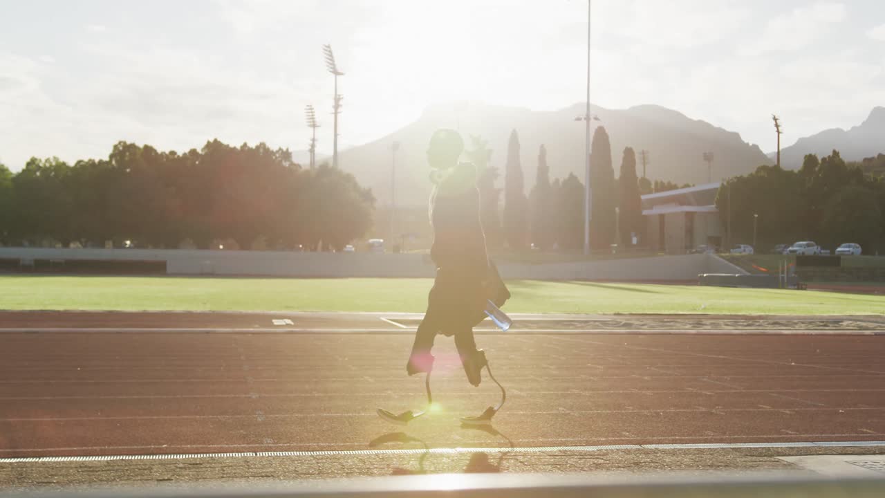 Disabled mixed race man with prosthetic legs walking on a race track