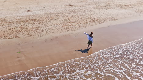 aerial view around a woman dancing on a tropical beach, sunny day in india