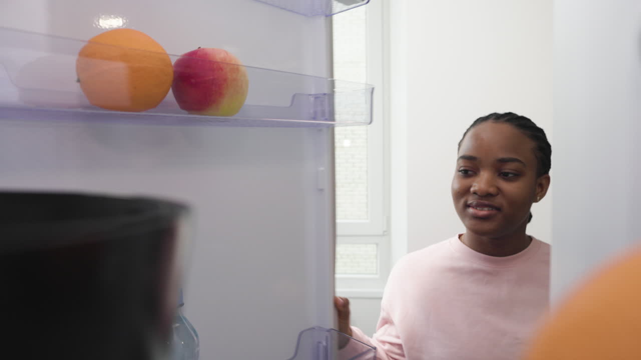 mujer tomando manzana del refrigerador