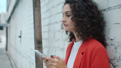 woman using smartphone next to a brick wall