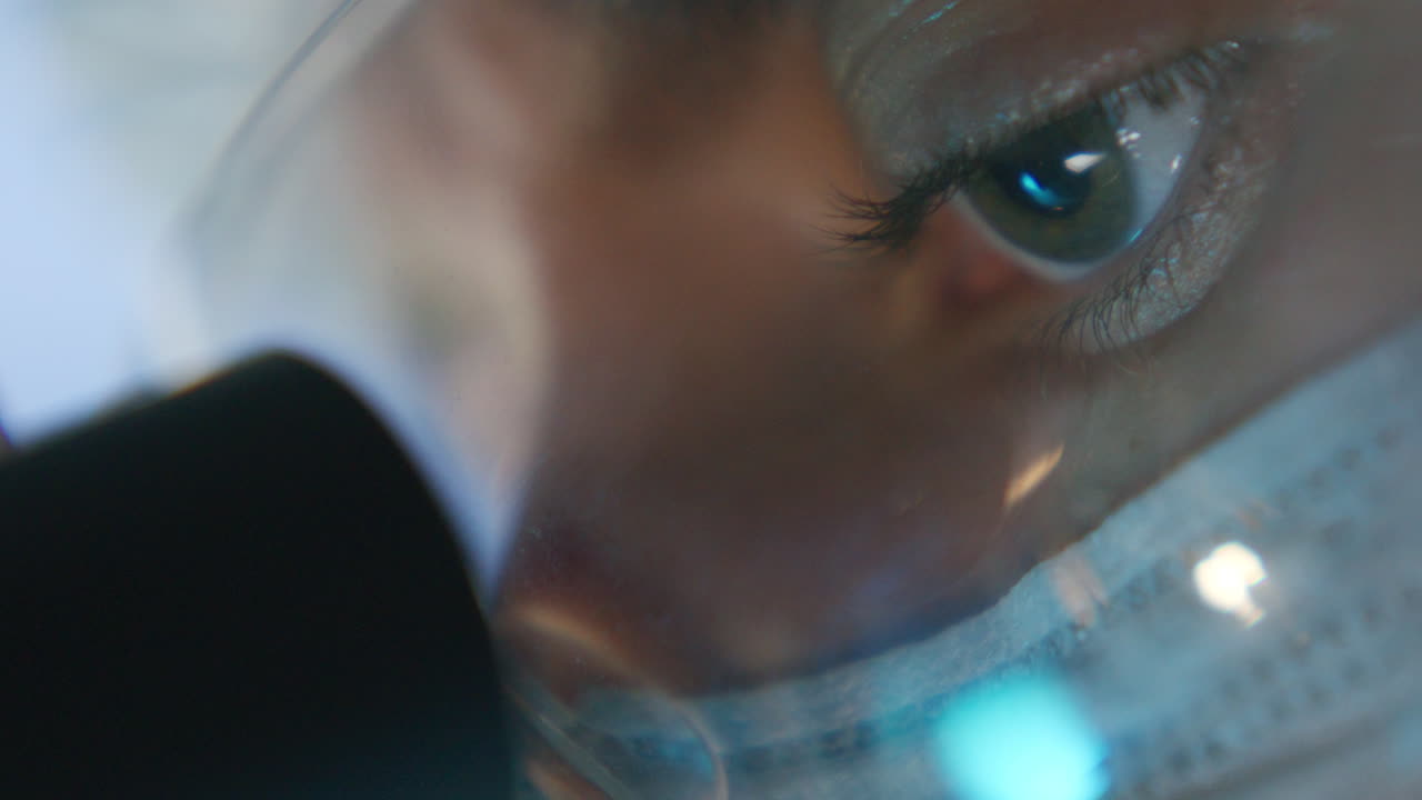 Extreme Close Up of Scientist Looking through Microscope during Research